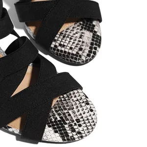 Detail of black and white snakeskin high heel sandals with elastic cross straps.