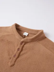Detailed view of brown fleece sweatshirt collar with button closure and size tag