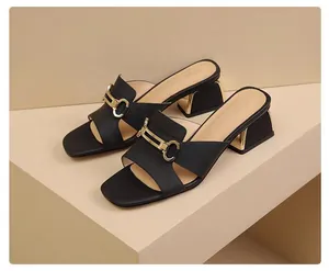 Elegante schwarze Sandalen mit Absatz und goldener Metallschnalle im Detail.