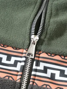 Nahaufnahme des Metallreißverschlusses und des Jacquard-Musters auf einem grünen Fleece-Hoodie