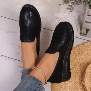 Detailed view showing the black platform slip-on shoes with shimmering textures