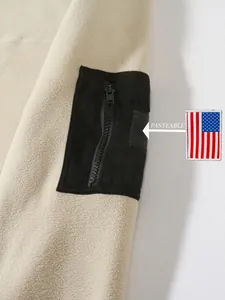 Nahaufnahme einer beigen Fleecejacke mit schwarzer Reißverschlusstasche und Klett