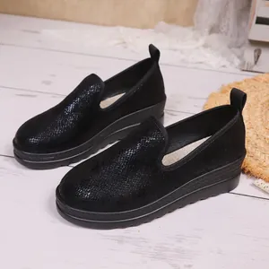 Side view of black textured platform slip-on loafers for women on white wood floor.