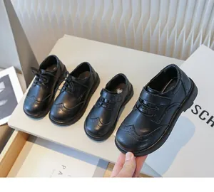 Close-up of boys' black leather dress shoes with brogue details and velcro strap