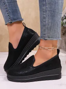 Close-up of black slip-on platform shoes for women with textured fabric finish.