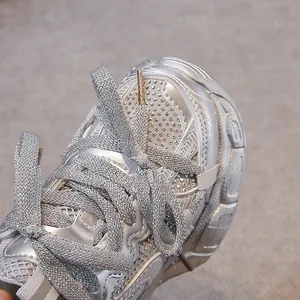 Close-up of silver kids' sneakers featuring shimmering laces and rhinestone details.