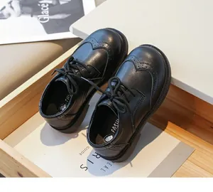 Detailed macro view of boys' black British-style brogue leather shoes with classic laces.
