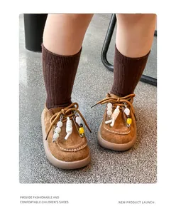 Vue détaillée de mocassins en daim vintage pour enfants avec épingles de sûreté et perles