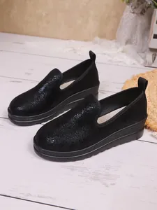 Detail view of black snakeskin texture on women's slip-on loafers with platform soles