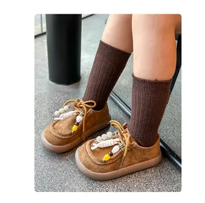 Détail de chaussures rétro en daim marron pour enfants avec des perles décoratives