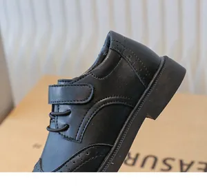 Close-up of black boys' formal leather dress shoes with brogue details and Velcro strap