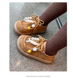Détail de chaussures en daim marron pour enfants avec des épingles décoratives