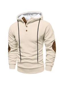 Detail view of a beige textured heavyweight hoodie with brown elbow patches and button collar