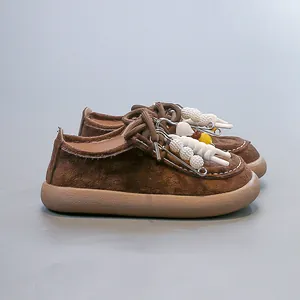 Gros plan de mocassins rétro en daim marron pour enfants avec breloques déco