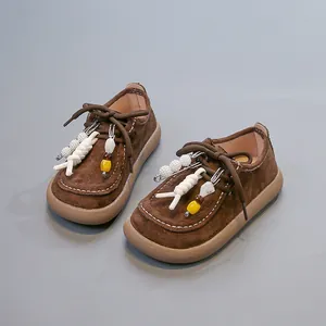 Détail de chaussures vintage en cuir marron pour enfants avec des charms en perles.