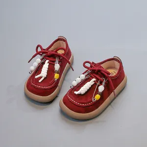 Vue détaillée de chaussures en cuir rouge pour enfants avec perles et glands décoratifs