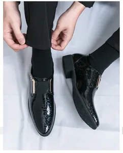 Nahaufnahme von schwarzen Herren-Lacklederschuhen mit spitzer Kappe und Metalldetails.