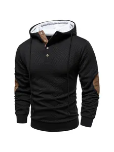 Detailed view of black textured hoodie with brown contrast button collar and patches