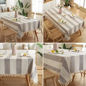 Vue détaillée de la nappe en coton et lin à rayures grises avec bords à pompons décoratifs.