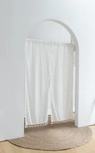 Macro detail of white fabric door curtain featuring orange polka dots and elegant tassel fringe