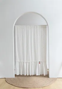 White cotton partition door curtain with yellow dots and ruffled hem in white archway