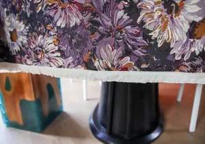 Close-up detail of high-density woven purple floral tablecloth with fringe edge
