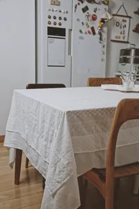 Close-up of white French lace tablecloth with floral embroidery in a home setting