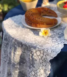 Primer plano de un camino de mesa de encaje blanco con bordados florales muy elegantes