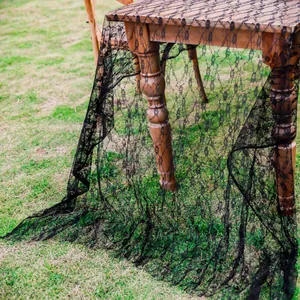 Détail d'une élégante nappe rectangulaire en dentelle noire sur une table rustique