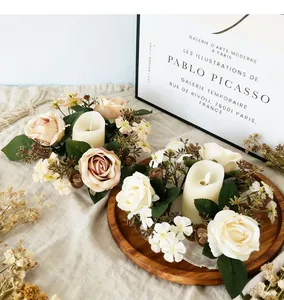 Close-up of decorative 3-head rose and wildflower candle ring wreath on wooden tray