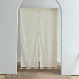 Detailed view of white fabric door curtain with orange dots and tassel fringe in archway