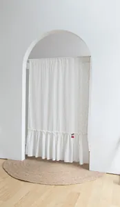 Detail of white cotton door curtain with yellow dots and a ruffled bottom hem