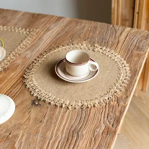 Close-up of a rustic round jute placemat with fringe detailing on a vintage wooden table