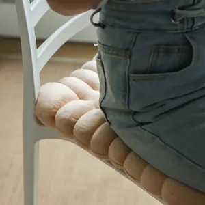 Macro detail of a soft biscuit-shaped plush chair cushion used on a white dining chair