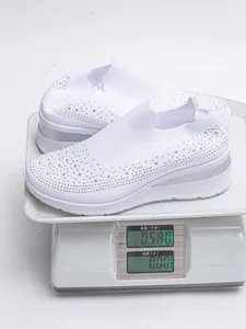 Sneaker slip-on bianche con strass dal peso di 0,58 kg su una bilancia digitale.