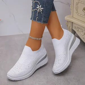 Dettaglio di scarpe slip-on bianche con strass brillanti e zeppa indossate da modella