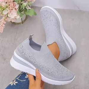 Dettaglio di eleganti sneaker grigie da donna con strass e suola platform in maglia.