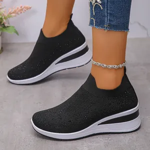 Dettaglio di sneakers nere in maglia da donna con zeppa e accenti in strass scintillanti.