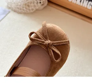 Primo piano di ballerine in camoscio marrone per bambina con fiocco decorativo