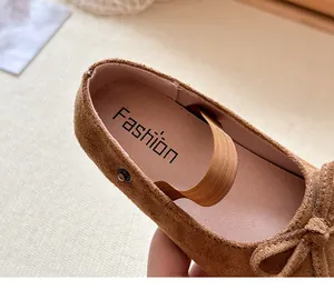 Dettaglio delle ballerine da bambina in camoscio marrone con fiocco e cinturino elastico
