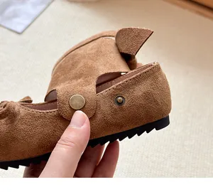 Dettaglio di una ballerina in camoscio marrone con chiusura a bottone a pressione
