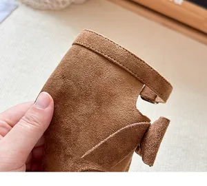 Vista dettagliata del materiale scamosciato marrone e del fiocco sugli stivali da bambina