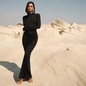 Elegant black ruched high-neck long-sleeved maxi dress for autumn, worn by a model in a desert.