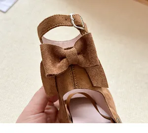 Primo piano di scarpa da bambina in camoscio marrone con grande fiocco e fibbia
