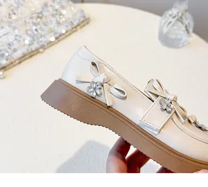 Dettaglio mocassini beige da bambina con fiocco e decorazione floreale in cristallo.