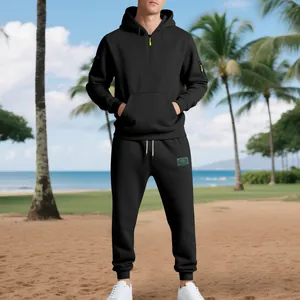 Men's black heavy fleece tracksuit set featuring a half-zip hoodie and jogger pants on a beach