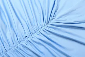 Macro view showing the elegant light blue ruched fabric texture of a slim-fit maxi dress.