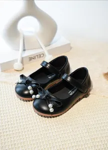 Détail de chaussures de princesse noires pour filles avec perles et nœuds élégants