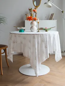 Vue détaillée d'une nappe en dentelle blanche brodée dans un décor rétro français.
