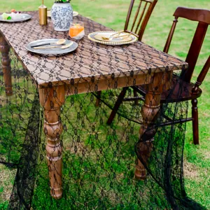 Vue détaillée d'une élégante nappe en dentelle florale noire sur une table en bois en extérieur.